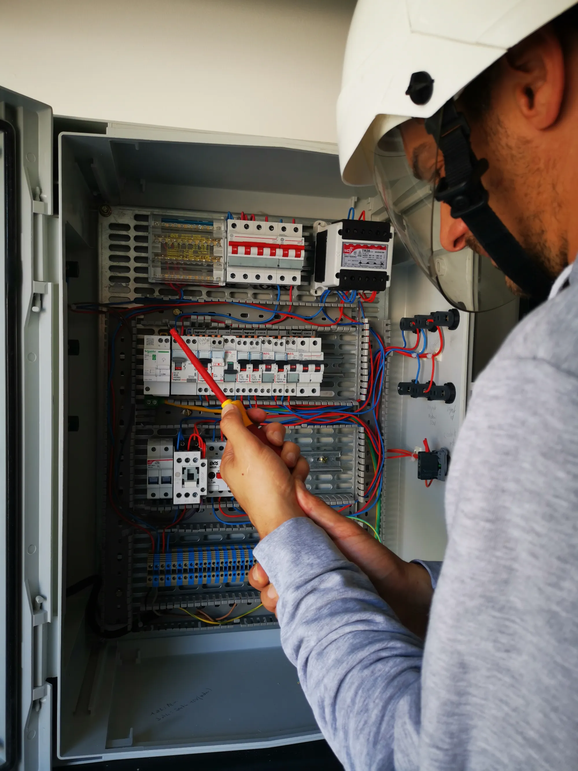 technicien-tableau-electrique Technicien vérifiant un tableau électrique avec un outil